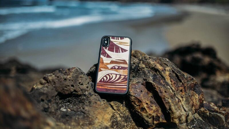 海岸の岩場に置かれたスマートフォンに装着されたラステックXアベル アーツ・サンセット・ウエスト